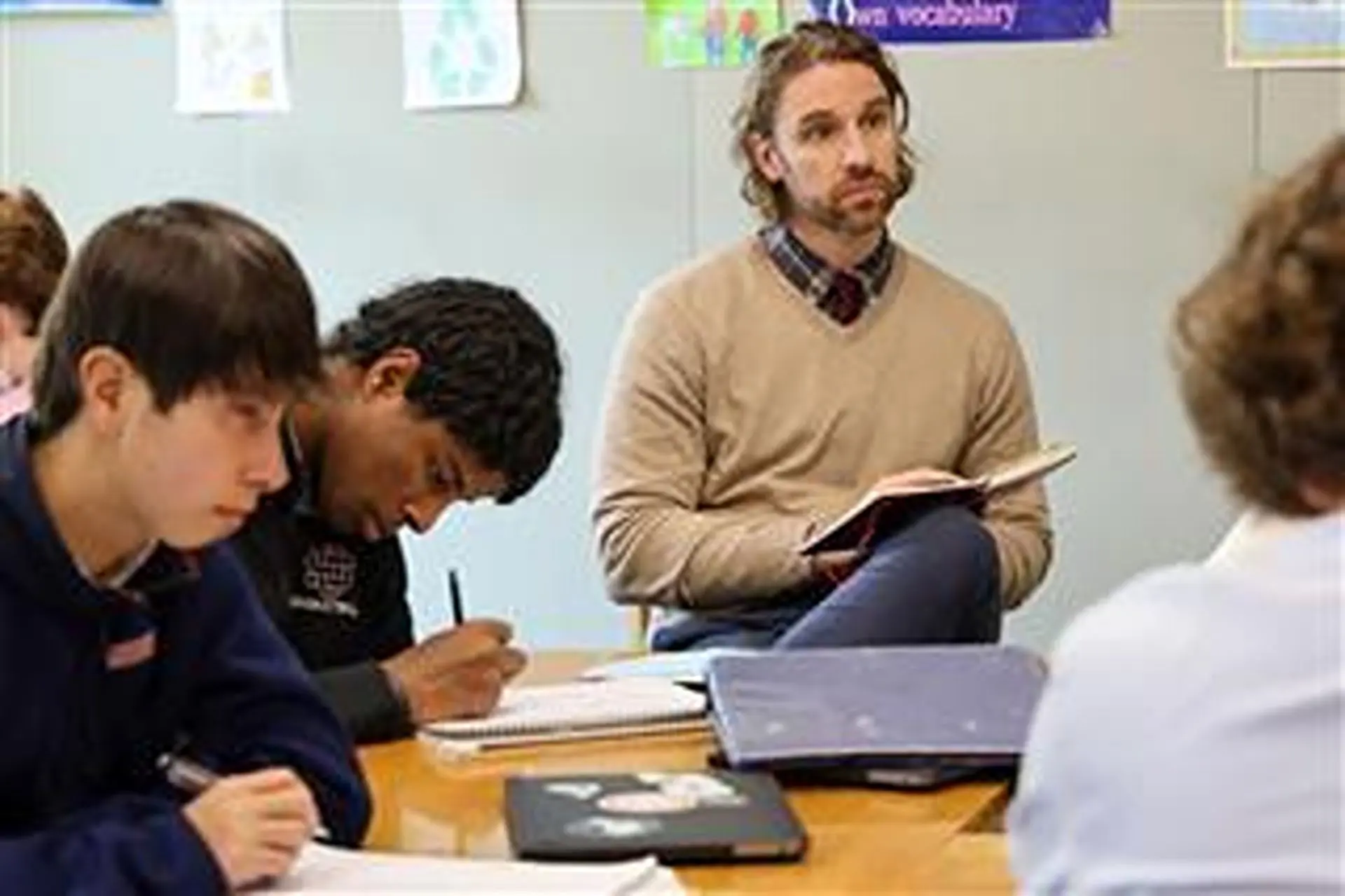 Dr. Tyler Yoder leading a history lesson, holding an open book while students take notes.