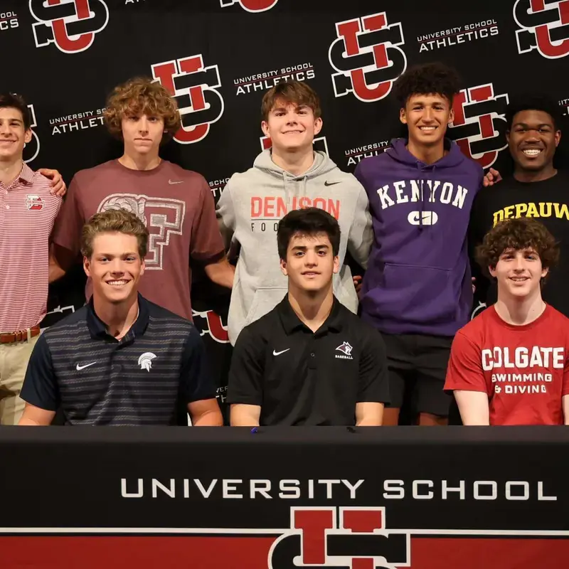 University School 2025 Collegiate Athletes wearing their college sweaters and posing for a photograph with a university school brand backdrop.