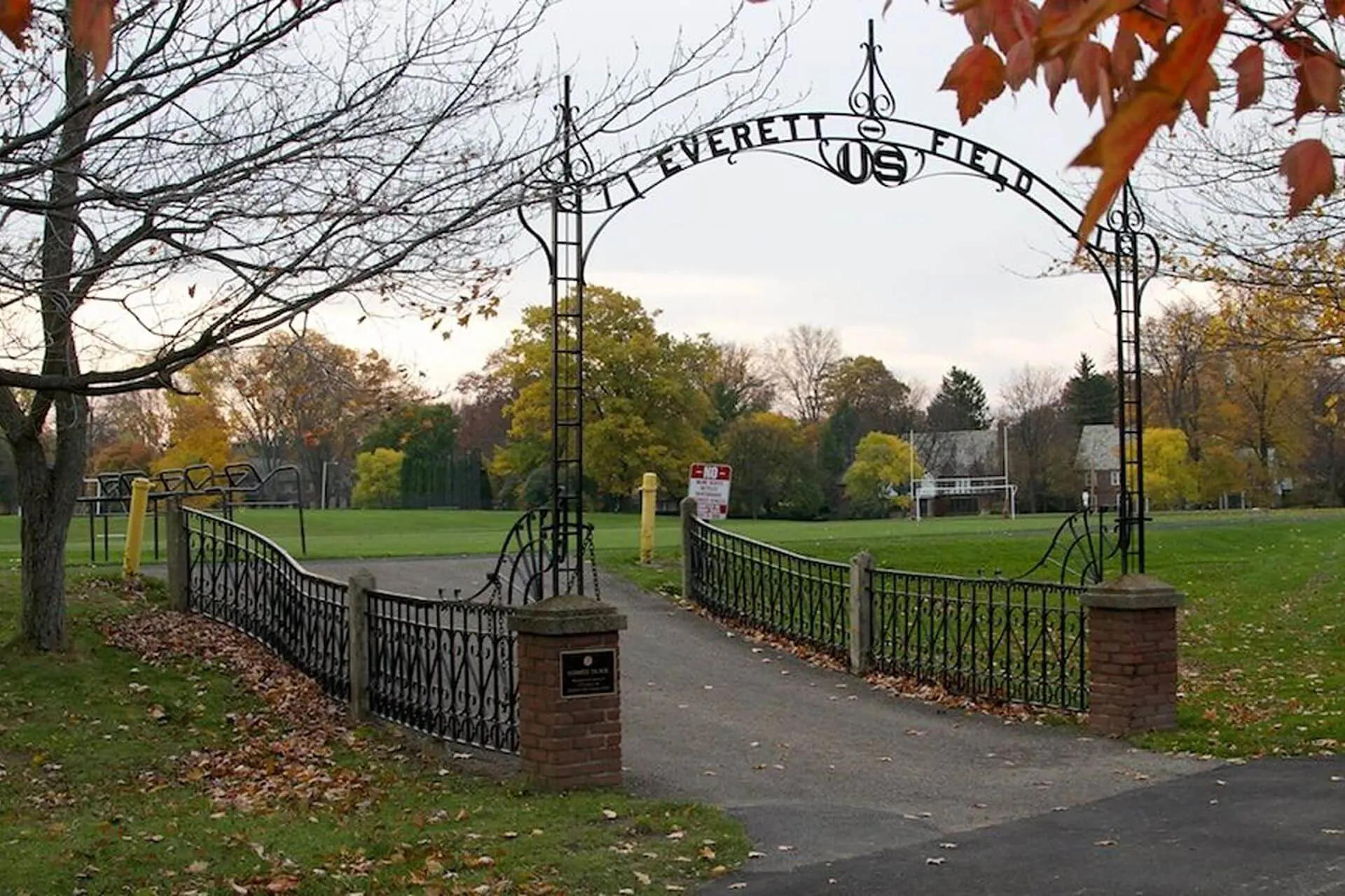 Autumnal view of the wrought iron Everett Field entrance at University School on an overcast afternoon.