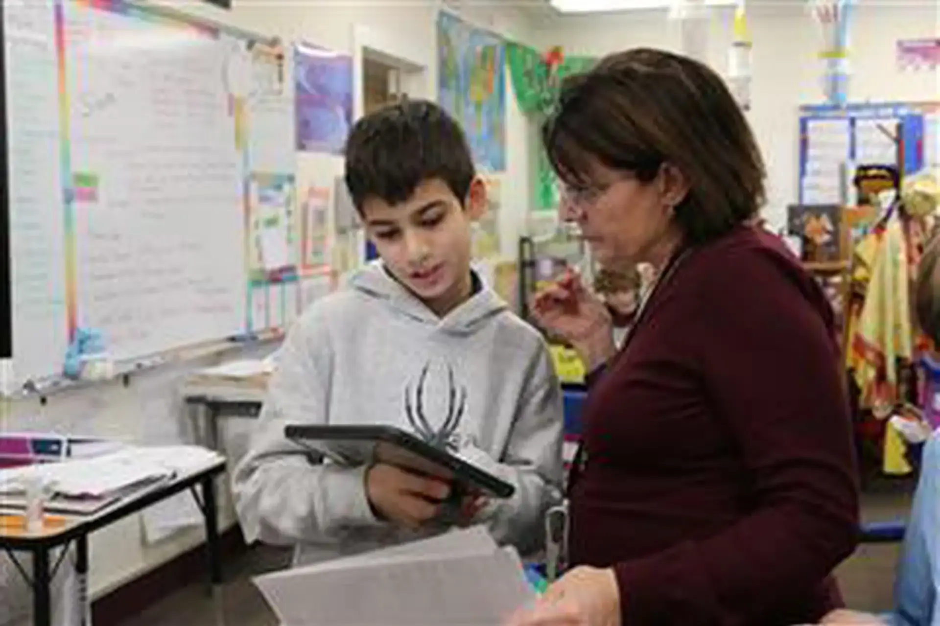 Ellen Rothfusz looking at classwork completed on a tablet with a student.