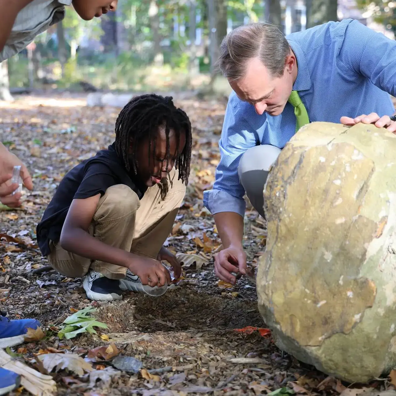University School student and teacher studying the insects found under a rock together.