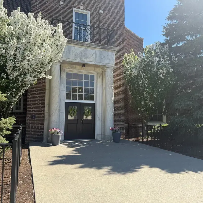 University School Shaker Campus Building Doorway in sunshine, surrounded by flowers and trees.