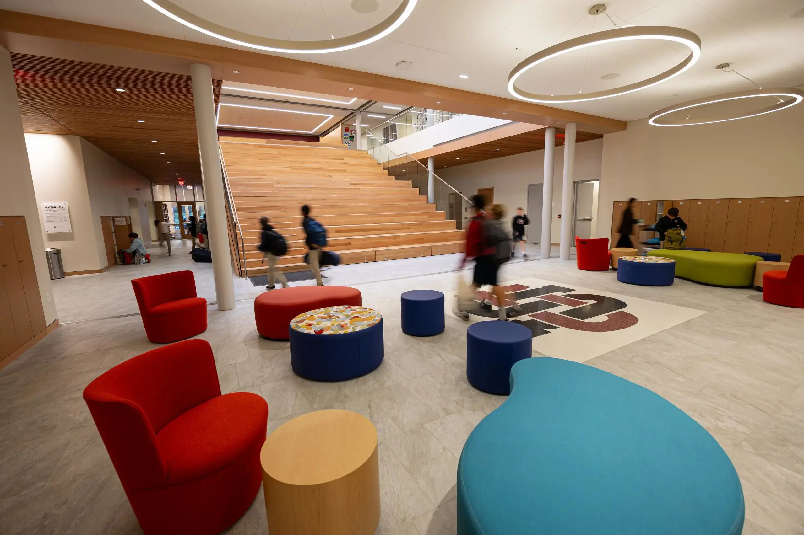 View of interior with red and blue sofas and a staircase at University School.