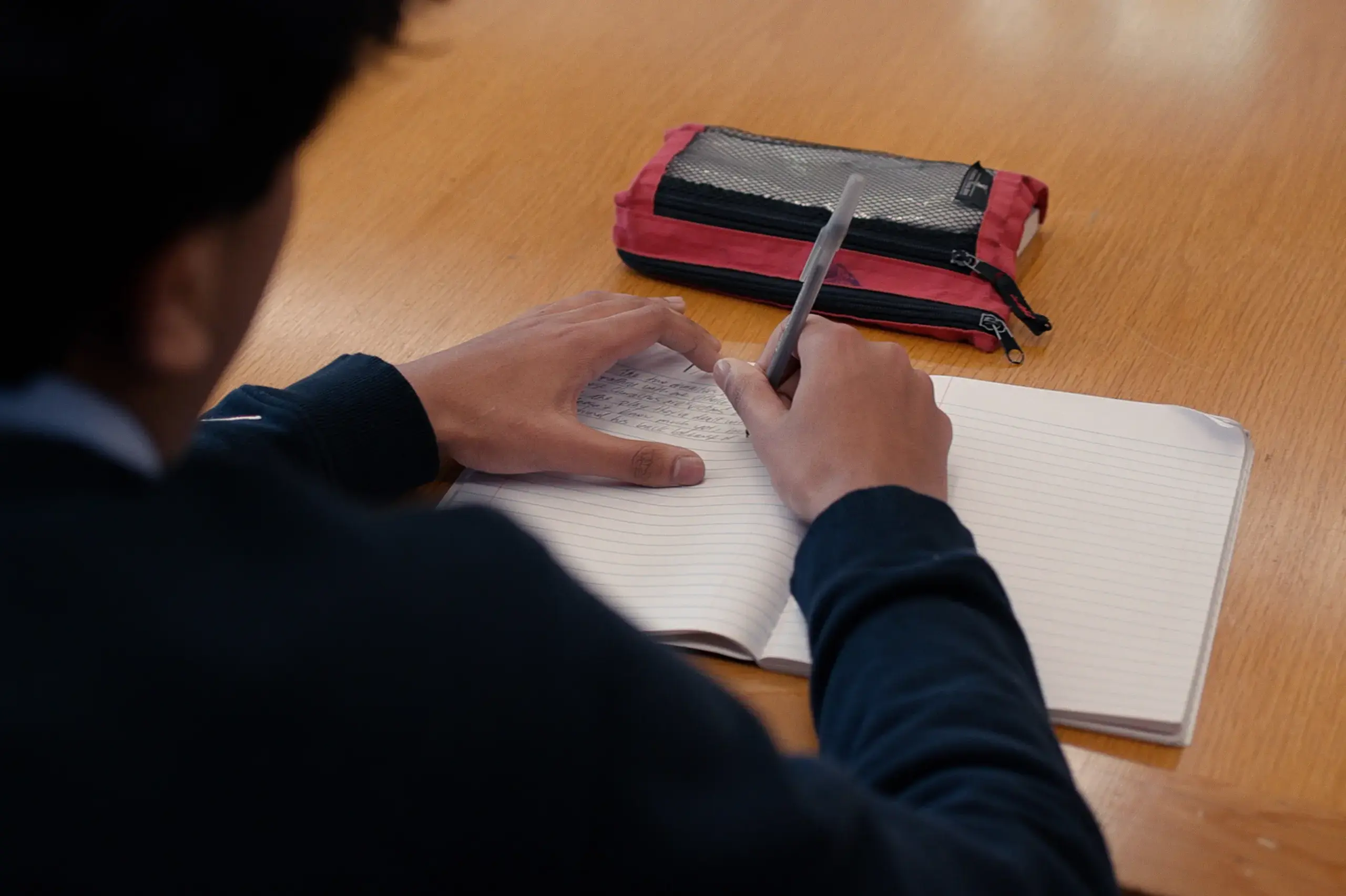 University School student at their desk writing in a notebook.