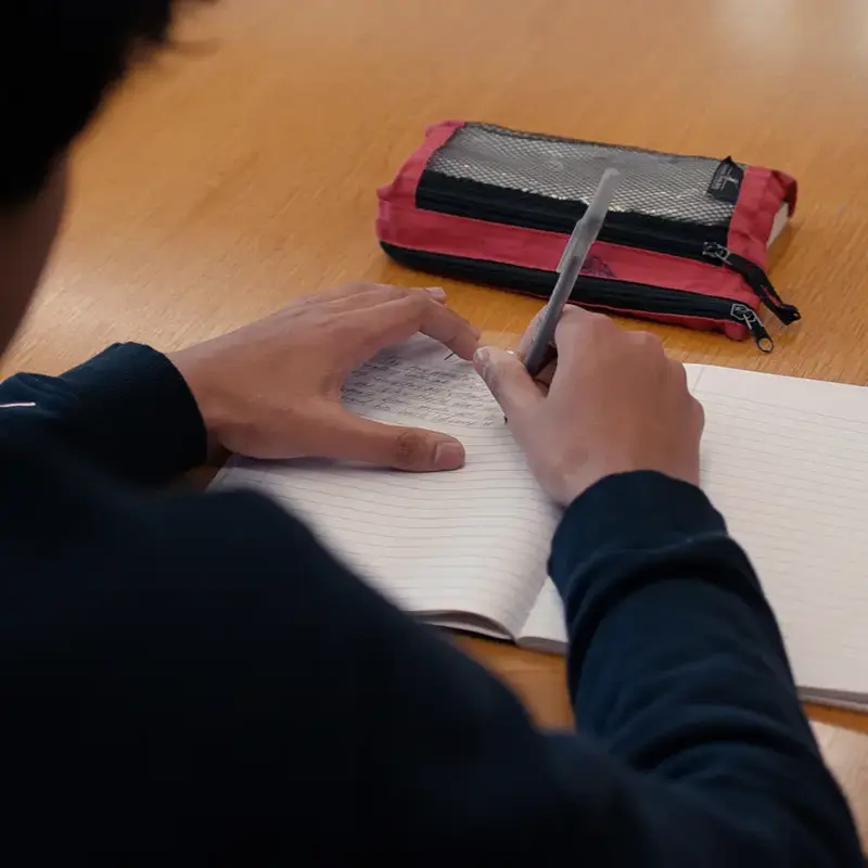 University School student at their desk writing in a notebook.