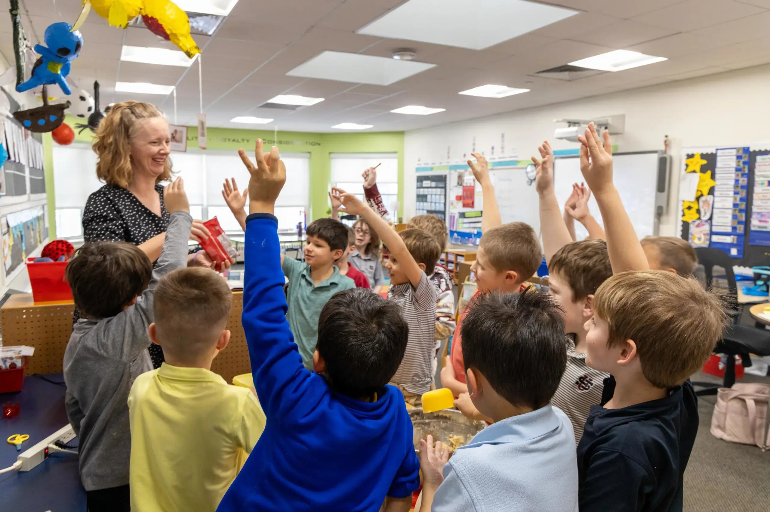 University School first graders standing around their teacher in a circle and raising their hands to answer a question.