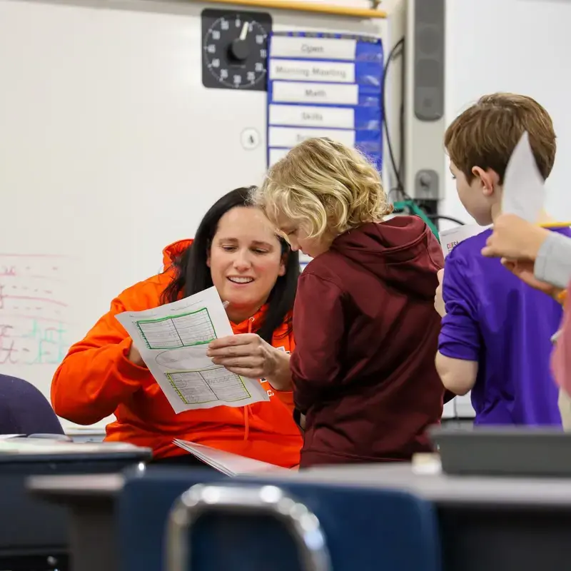University School second grade teacher looking at worksheet with a student.