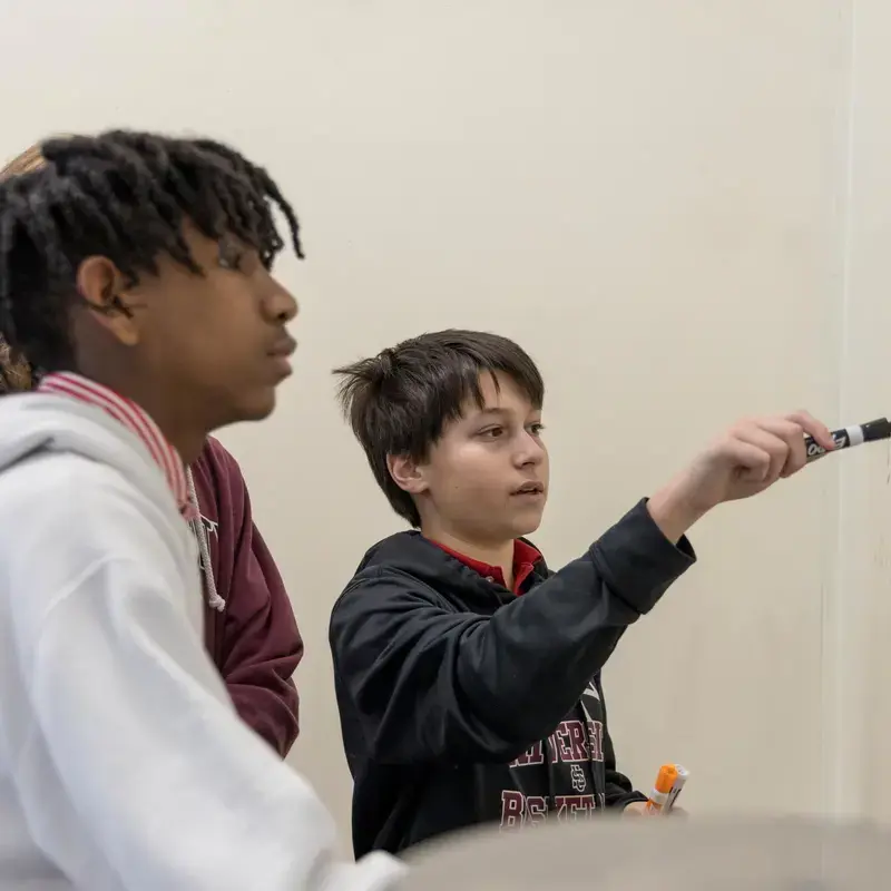 University School Middle School students solving equations together on the whiteboard in a math class.