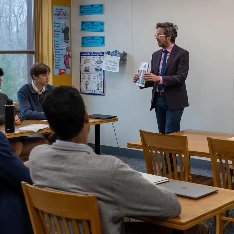 University School Upper School teacher showing a textbook to students in a language class.