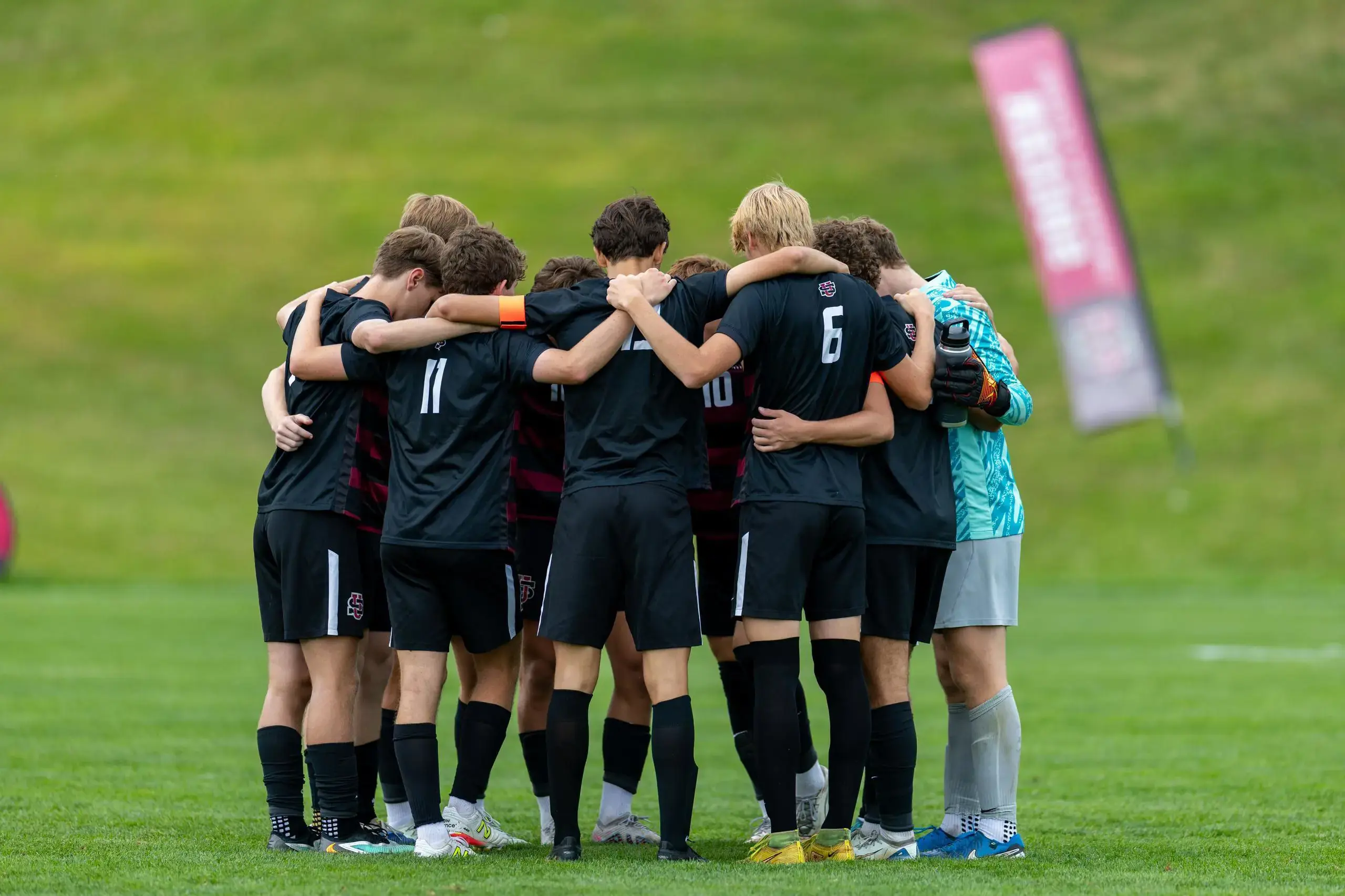 University School Upper School Soccer team huddling on the pitch.
