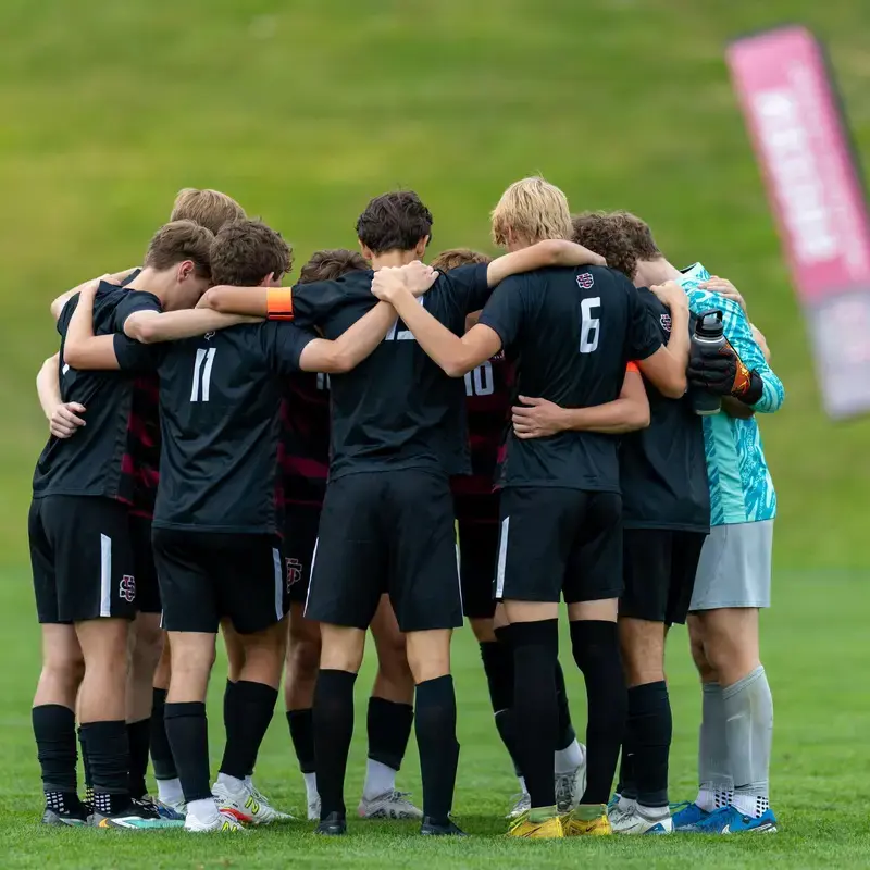 University School Upper School Soccer team huddling on the pitch.